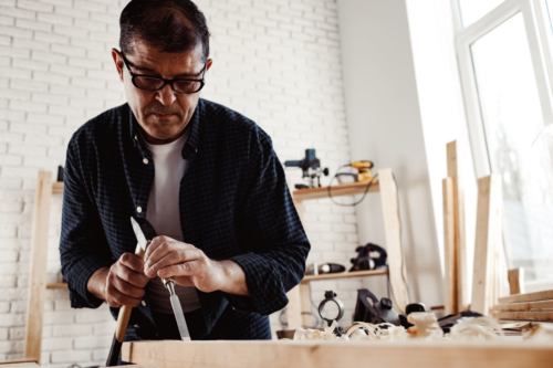 A carpenter works with a hammer and chisel