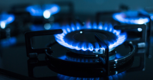 Four burners glow blue on a natural gas stovetop.